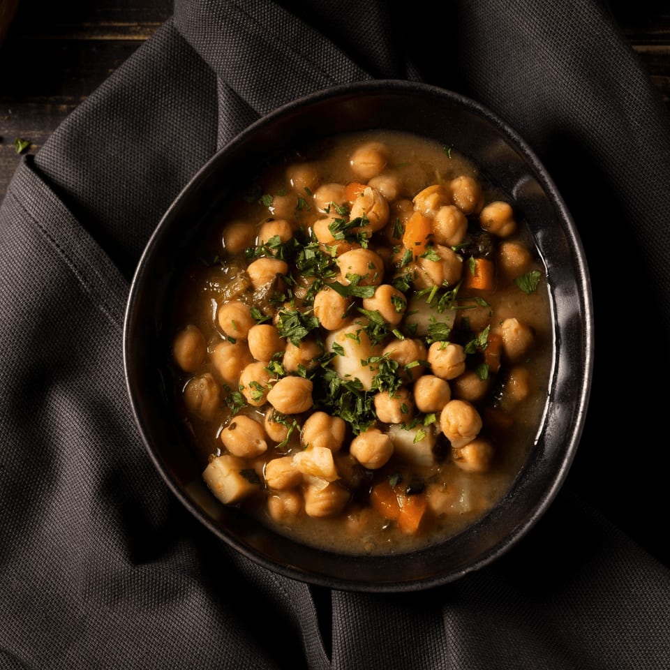 Overhead view of a black bowl filled with chickpea curry, garnished with fresh parsley.