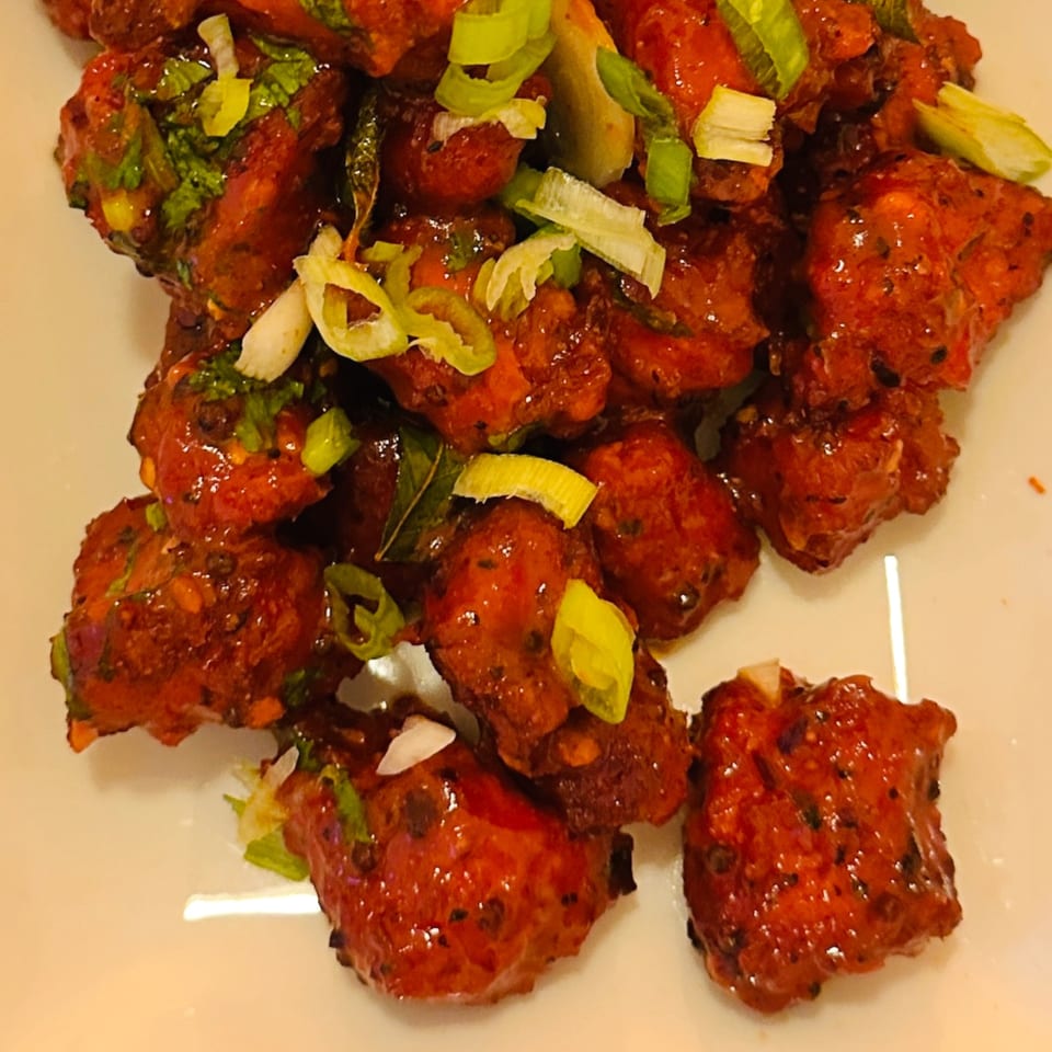 CURRYZONE's Indian chili chicken, glistening with sauce and garnished with fresh green onions.