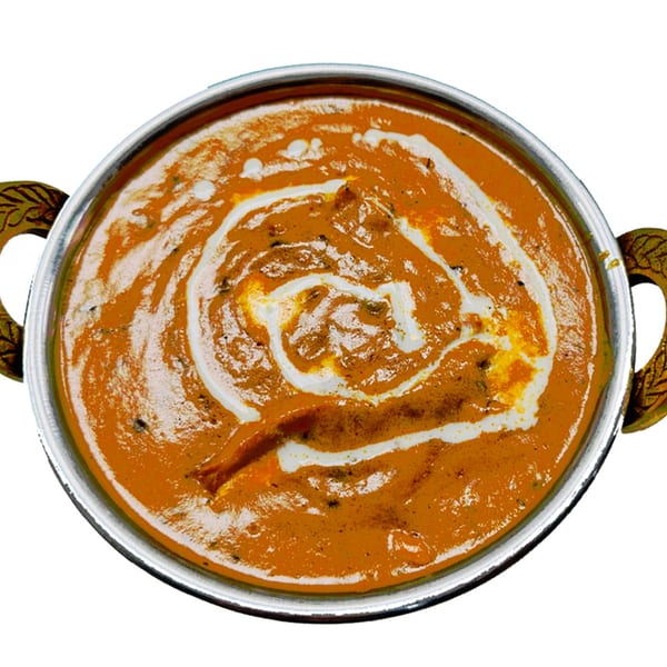 Overhead view of a rich orange Indian curry with white cream swirls in a metal bowl.